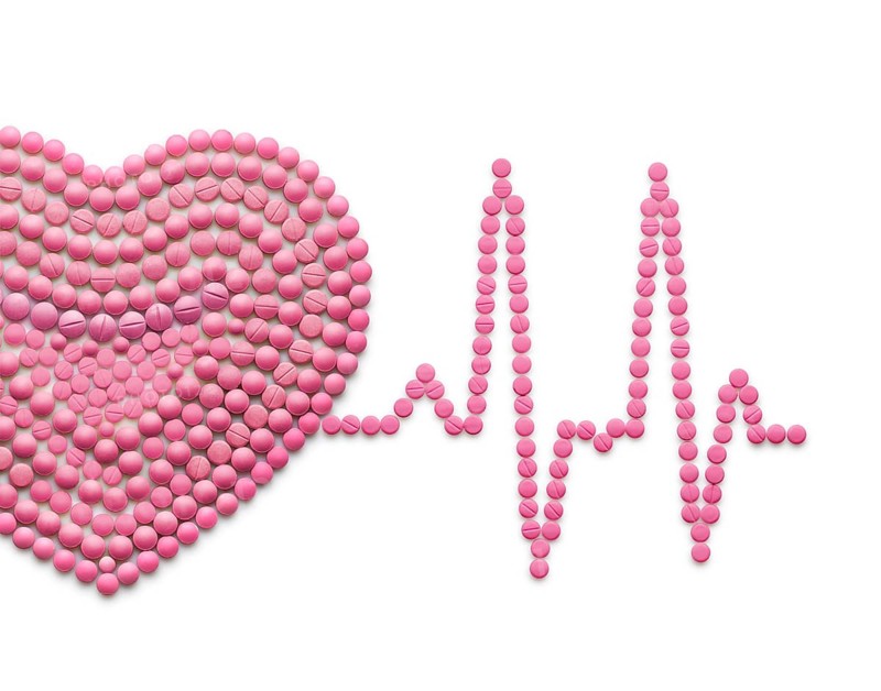 Creative medicine and healthcare concept of drugs and pills, against a white background ECG, a human heart with a heartbeat line
