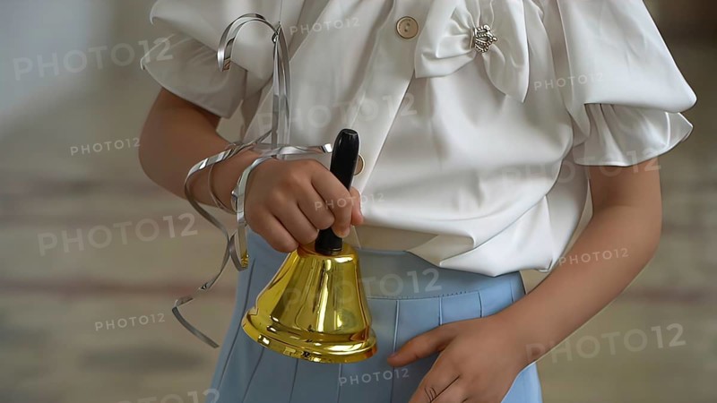 Little girl ringing a bell in the school classroom, closeup