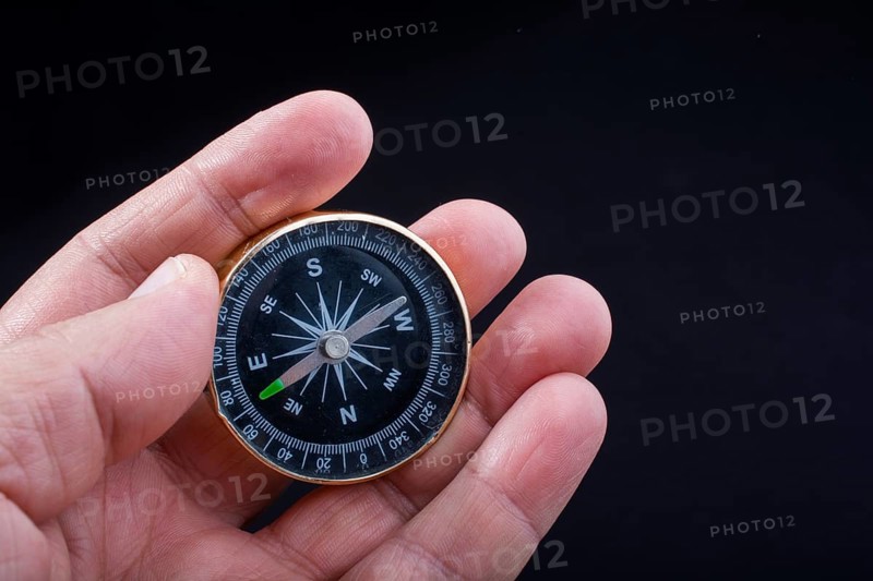 Child hand holding a compass on a black background