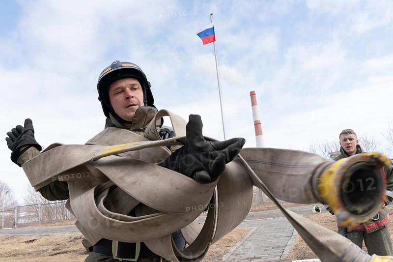 PETROPAVLOVSK CITY, KAMCHATKA PENINSULA, RUSSIA, APR 19, 2019: Firefighter-rescuer Emercom of Russia collects long fire hose on hands. Firefighters and rescuers (fire-fighting) sport competitions