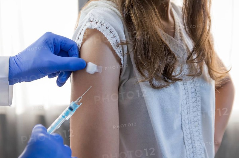 Close up doctor holding syringe and using cotton before make injection to patient in medical mask. Covid-19 or coronavirus vaccine