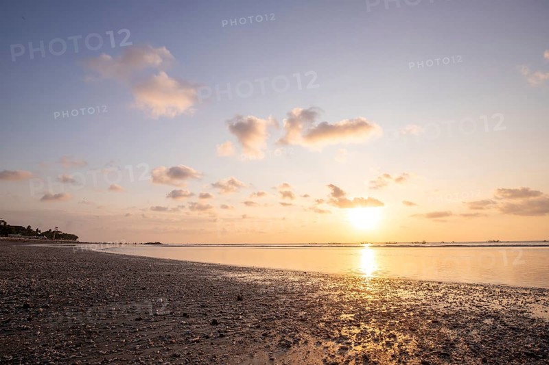 Dreamlike sunset on the dream beach of Kuta, small waves sunset over the sea and the reflection of the sky in the shallow water. Topical Bali in Indonesia