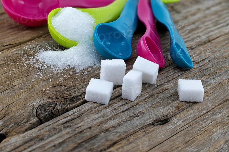 Array of sugar presentations on a wooden table, showcasing sugar cubes and granulated sugar