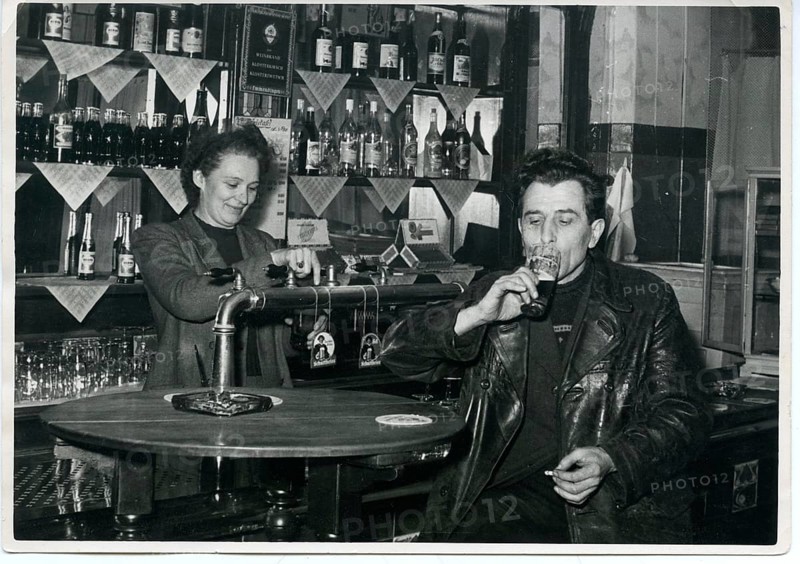 Pub, landlady, man drinking beer at the bar, smoking, 1960s, Germany, Europe