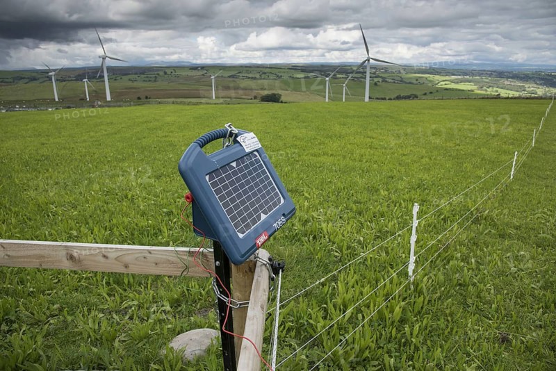 Solar powered electric fencing in pasture, with wind turbines in the background, Adfa, Newtown, Powys, Wales