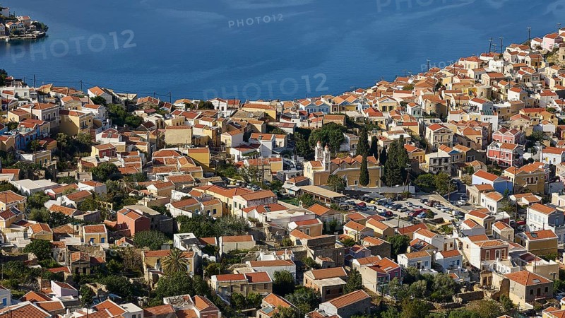 Dense cluster of houses overlooking the sea beyond, Symi Town, Symi, Dodecanese, Greek Islands, Greece, Europe