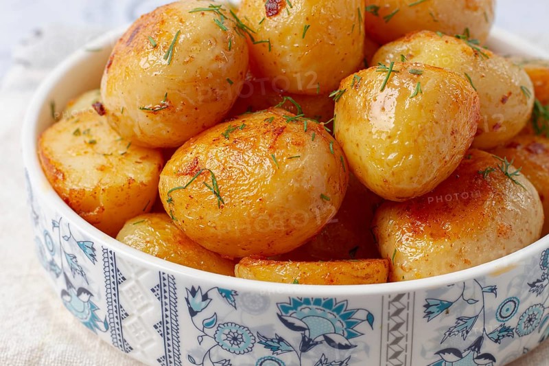 Baked new potatoes, with butter and dill, on a white plate, at home, no people