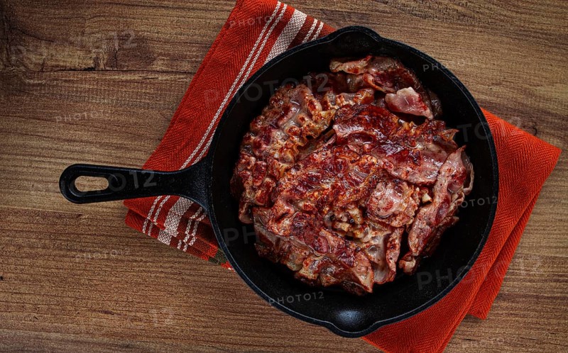 Crispy bacon, on a cast-iron skillet, on a wooden table, rustic style, no people