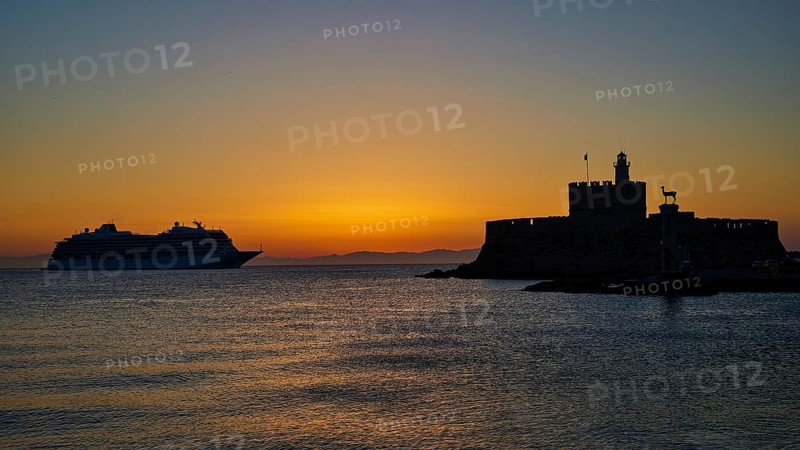 Cruise ship passing a fortress, calm, warm sky, sunrise, dawn, Fort of Saint Nikolaos, Mandraki harbour, Rhodes town, Rhodes, Dodecanese, Greek Islands, Greece, Europe