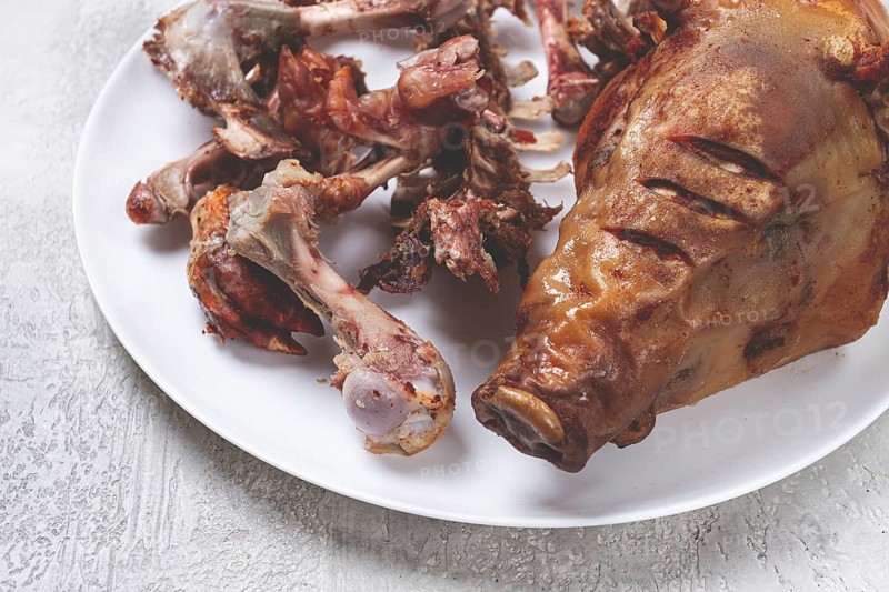 Roast pork head, with remnants of bones and meat, on a white platter, no people, close-up