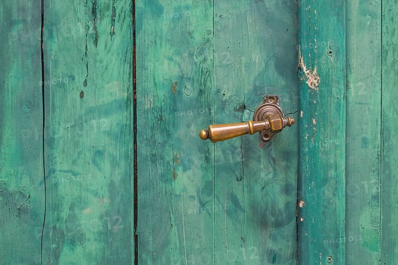 Old green wooden door with peeling paint and metal handle, metal latch, Croatia, Europe