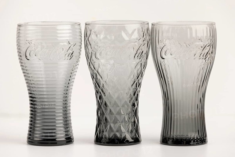 Three stylish, differently designed cola glasses in transparent and black tones