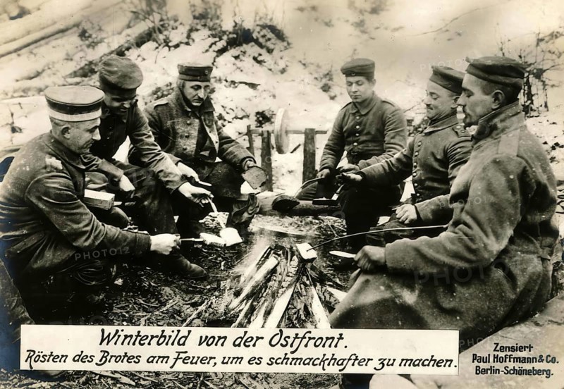 Winter picture from the eastern front. Roasting bread by the fire to make it more flavourful, 1914 - 1918, World War I, reproduction of a war postcard