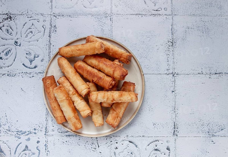 Fried spring rolls with cheese, on a plate, with cream sauce, no people