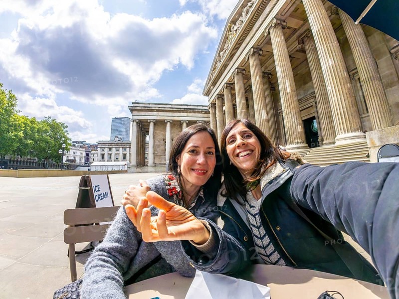 Two happy female tourists taking a selfie with fisheye lens in front of the british museum in london, uk