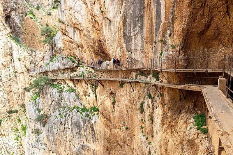 People walking on the narrow Caminito del Rey path that runs along a dramatic cliff face, Malaga, Spain, Europe