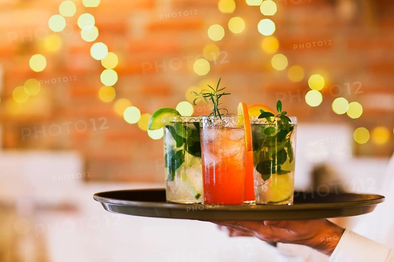 Two cocktail glasses on tray on wooden bar counter