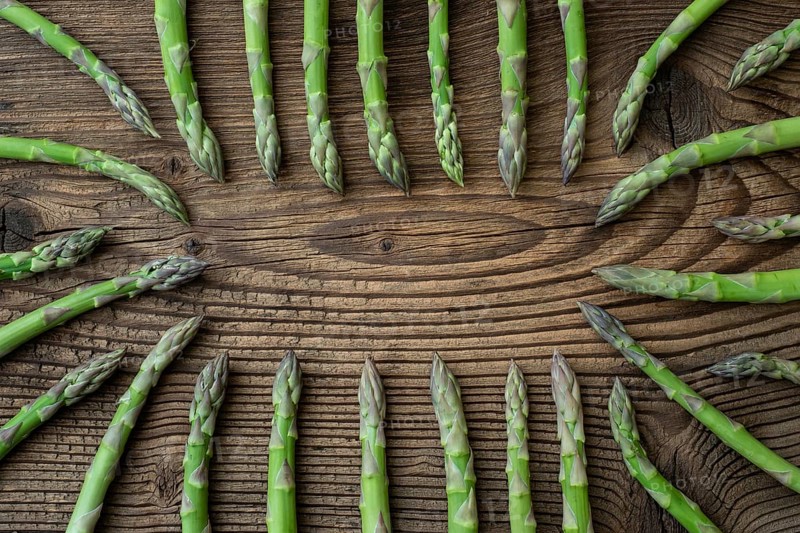 Raw garden asparagus stems. Fresh green spring vegetables on wooden background. (Asparagus officinalis)