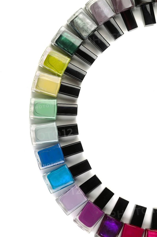 Flaschen mit Nagellack in einem Halbkreis angeordnet. Vertikaler Rahmen. Isoliert auf Weiß