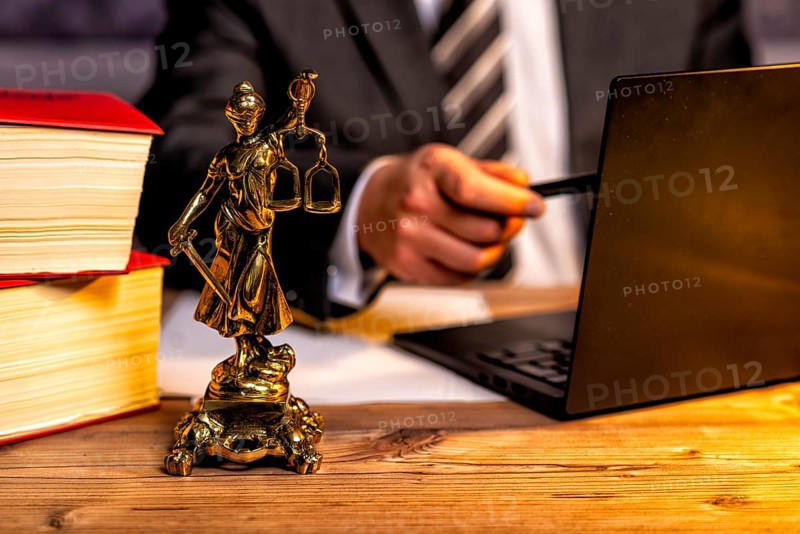 Office of a lawyer with books and a statue of Lady Justice, goddess Justitia, on the desk