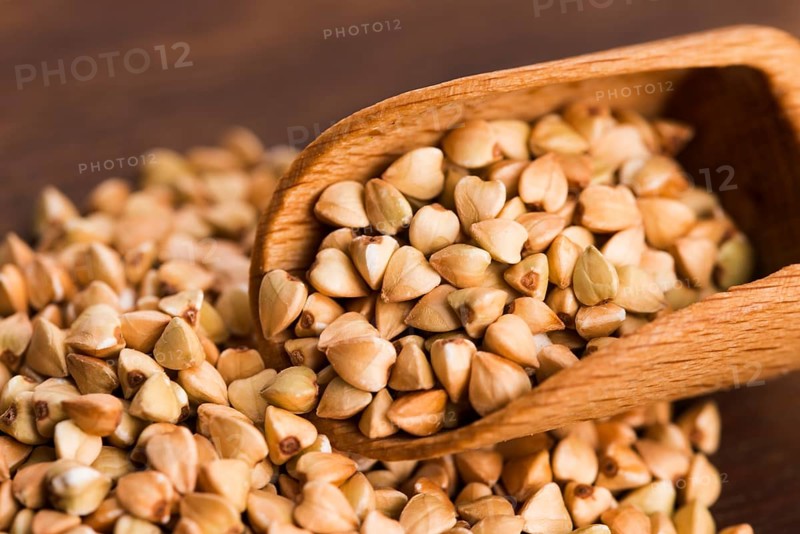 Buckwheat with a spoon on a wooden board background