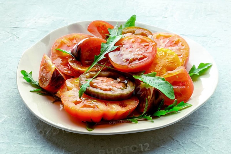 Fresh tomato and rocket salad. A variety of tomatoes of different sorts with arugula leaves. Healthy summer food, Food photography, Food photography