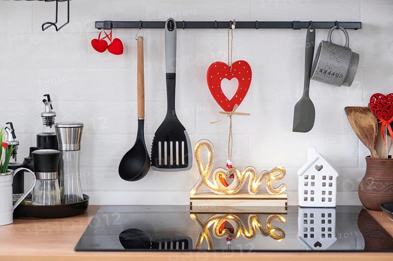 The interior of the kitchen in the house is decorated with red hearts for Valentine's Day. Decor on the table, stove, utensils, festive mood in a family nest