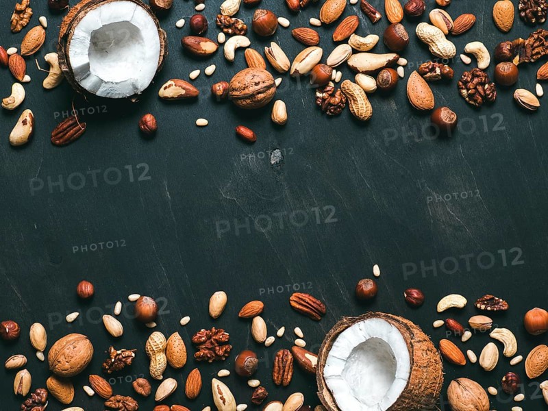 Background of mixed nuts - coconut, hazelnuts, walnuts, almonds, pecan, pistachio, brazil nut, pine nuts, peanut - on dark background. Copy space. Top view or flat lay