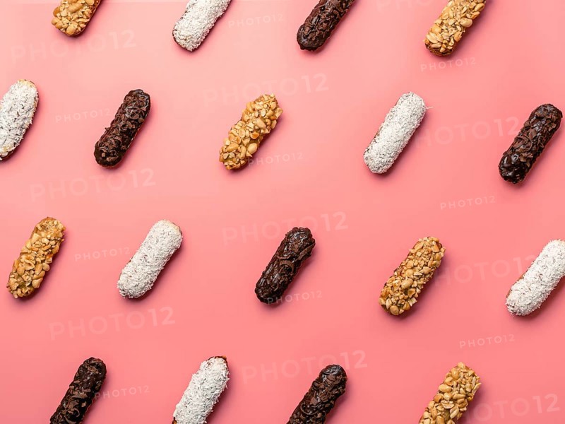 Pattern of different homemade eclairs on pink background. Top view of delicious healthy profitroles with different decor - chocolate, peanut and sherdded coconut