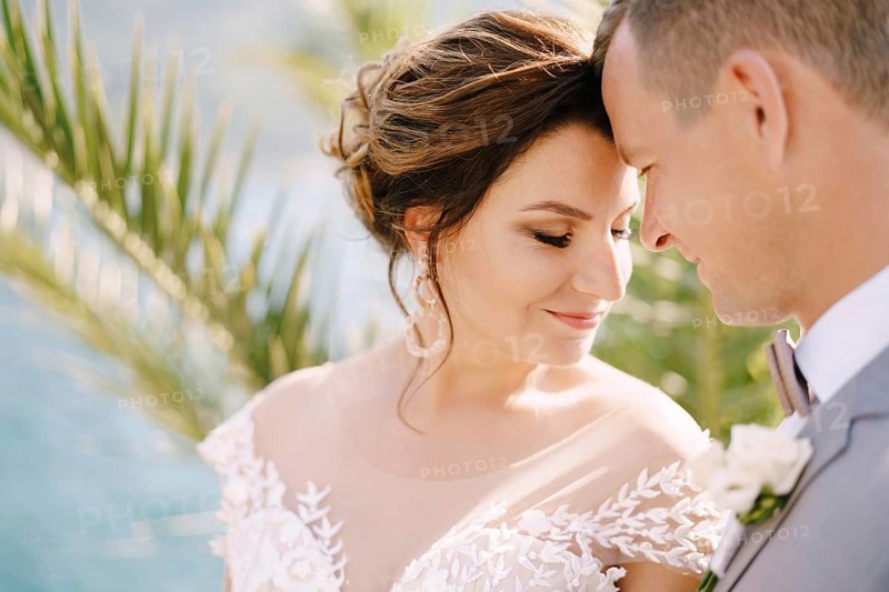 Smiling groom pressed his forehead to bride forehead.