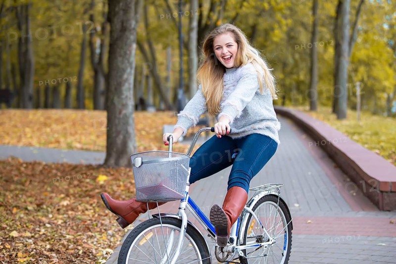 Young beautiful woman rides a bicycle in the autumn park
