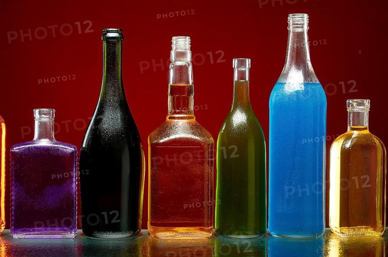 Verschiedene alkoholische Getränke in transparenten Flaschen auf rotem Hintergrund