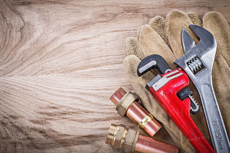 Safety gloves copper water pipe wrench hose nipples adjustable spanner on wooden board plumbing concept