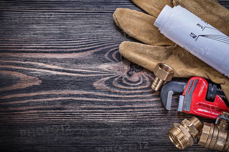Working gloves pipe wrench engineering drawings brass plumbing fittings on wooden board copy space
