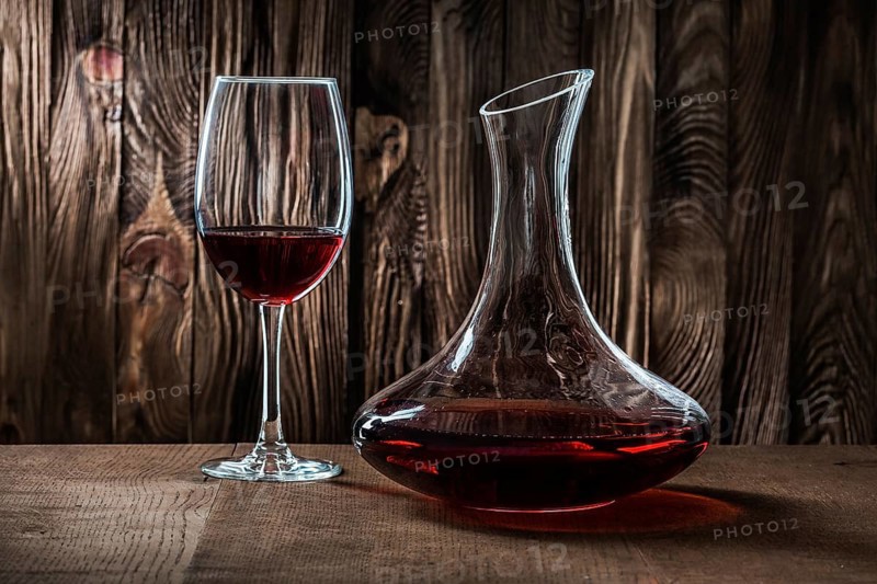 Decanter and glass with red wine on vintage wooden background