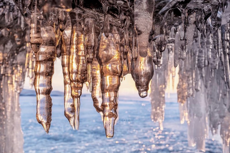 Ice cave on Baikal lake in winter. Blue ice and icicles in grotto in the sunset sunlight. Olkhon island, Baikal, Siberia, Russia, Europe