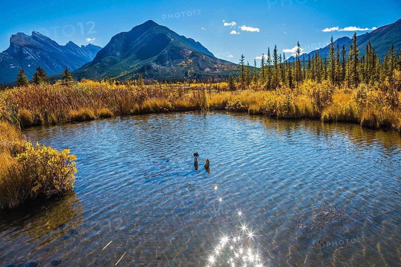 Magic Vermillon lake in the Rocky Mountains of Canada. Solar glare in smooth water. Concept of active tourism and ecotourism