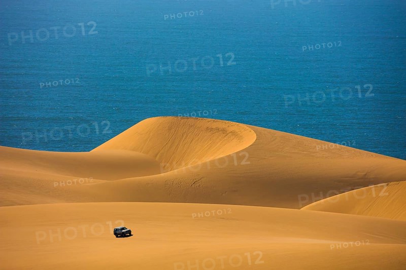 Dangerous and gorgeous jeep - safari through the huge sand dunes on the ocean shore. Atlantic coast of Namibia, south of Africa. The concept of exotic and extreme tours