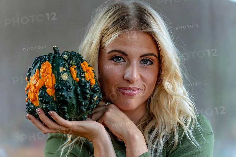 A stunning blonde model poses in a vibrant pumpkin field, wearing a stylish autumn outfit with a touch of Halloween charm. The setting glows with warm orange hues and festive seasonal vibes, New Braunfels, United States of America