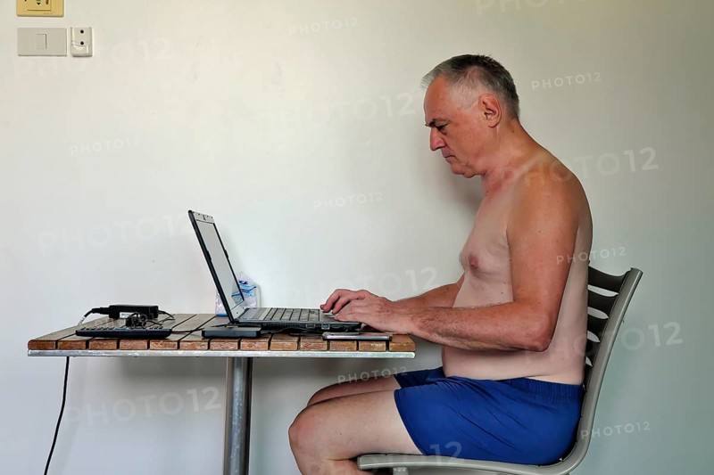 Businessman, freelancer, 60 plus on holiday working with laptop and mobile phone, Pattaya, Chonburi, Thailand, Asia