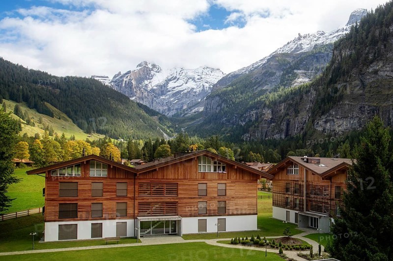 Wooden chalet in Kandersteg village, Canton Bern, Switzerland, Europe, Autumn trees and mountains panorama, Europe