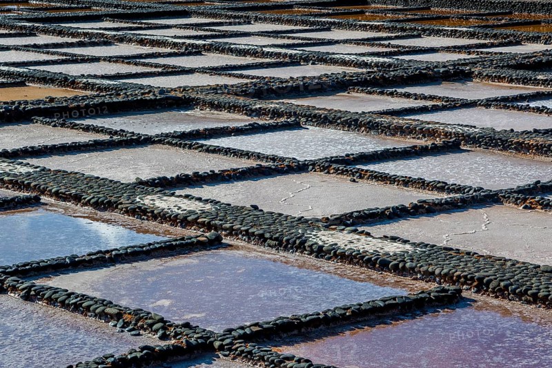 View on traditional rectangular salt evaporation ponds or salt pans creating a grid showing different stages of evaporation and concentration