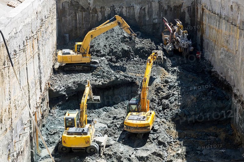 Excavators dig at a construction site of a street and a subway. Baggers transport dirt to a higher level to make room for the subway digging machine. Working fast and efficient