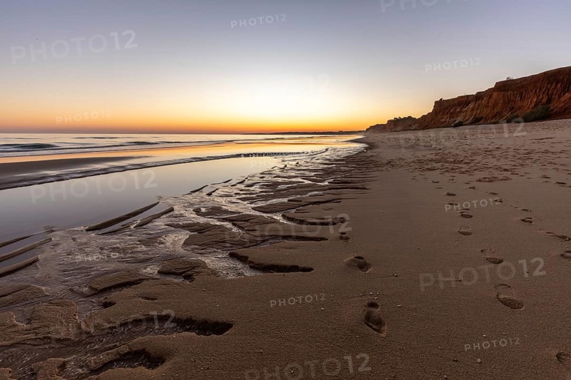 What a sandy beach on the Atlantic. Landscape shot at sunset on a coast with sandstone cliffs. Low tide on the yellow beach of Praia da Falésia near Albufeira, Algarve, Portugal, Europe