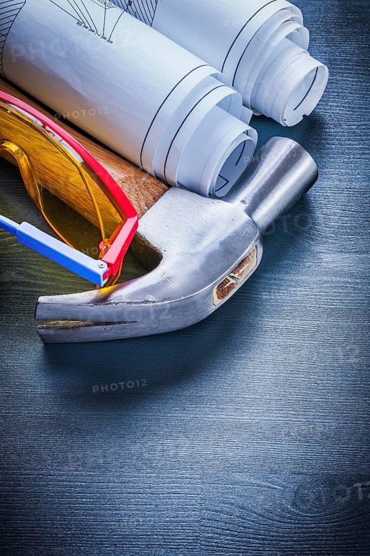 Close up rolled up blueprints hammer goggles