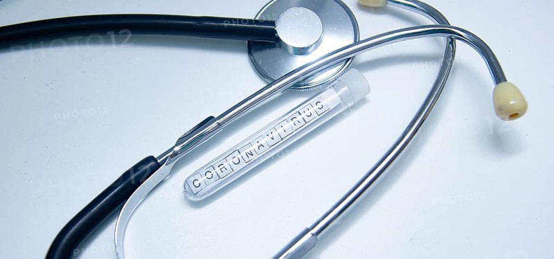 Coronavirus-labeled test tube beside a stethoscope on a white background