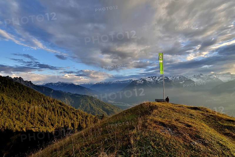 Sitting woman enjoying a dreamlike evening mood in the mountains, view to the Rätikon, flag of the Austrian Alpine Club, Frassenhütte, Vorarlberg, Austria, Europe