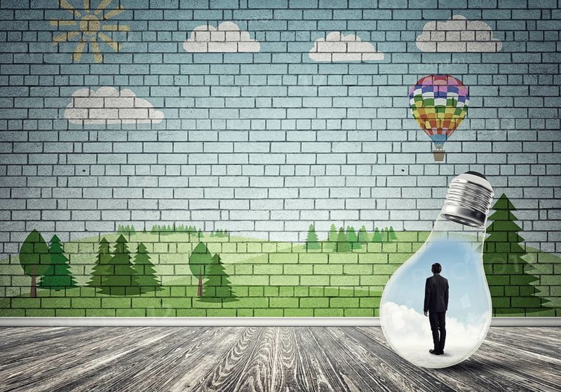 Businessman inside light bulb in room against nature drawn concept
