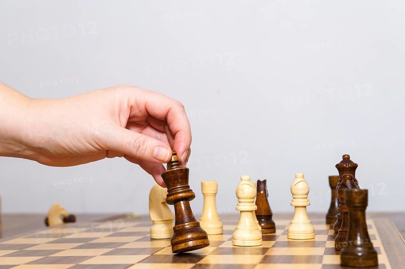 Close-up of a woman's hands playing chess with a white background and copy space