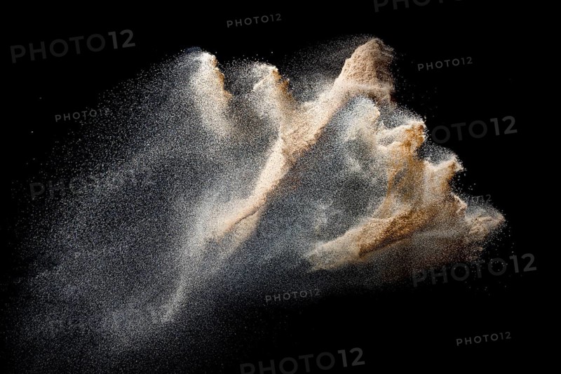 Sand flying explosion isolated on black background. Freeze motion of sandy dust splash